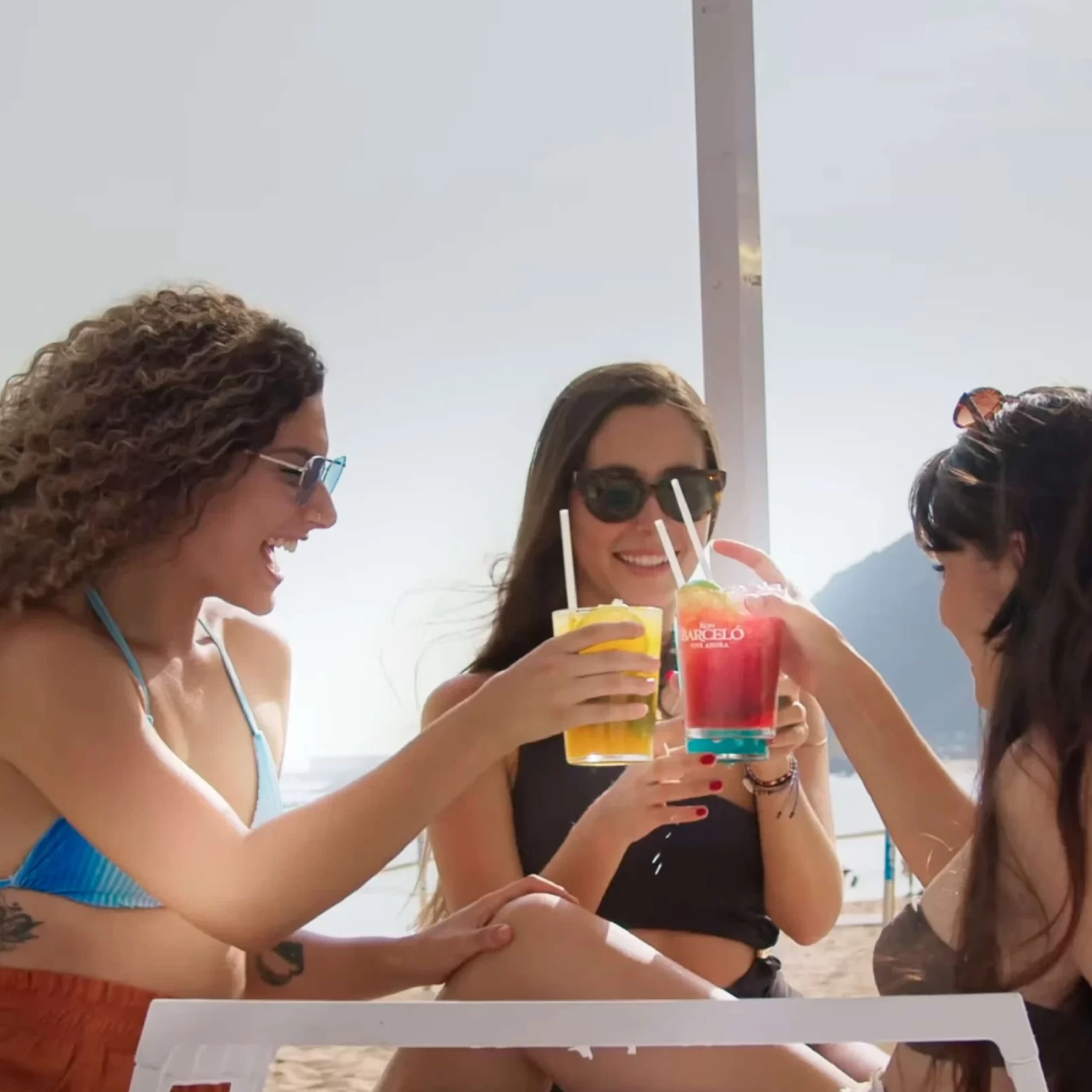 Tres chichas brindando en la playa.