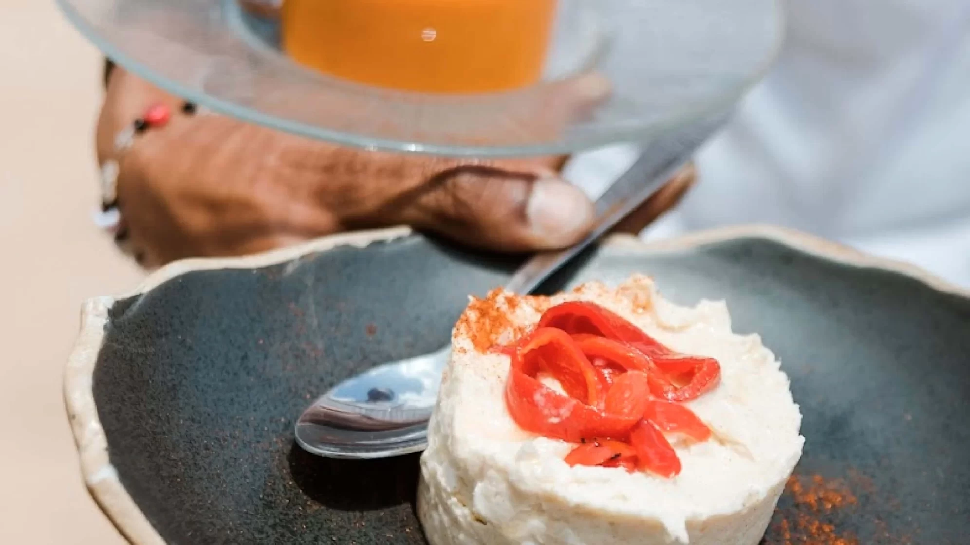 Camarero sostiene un plato de ensaladilla y salmorejo.