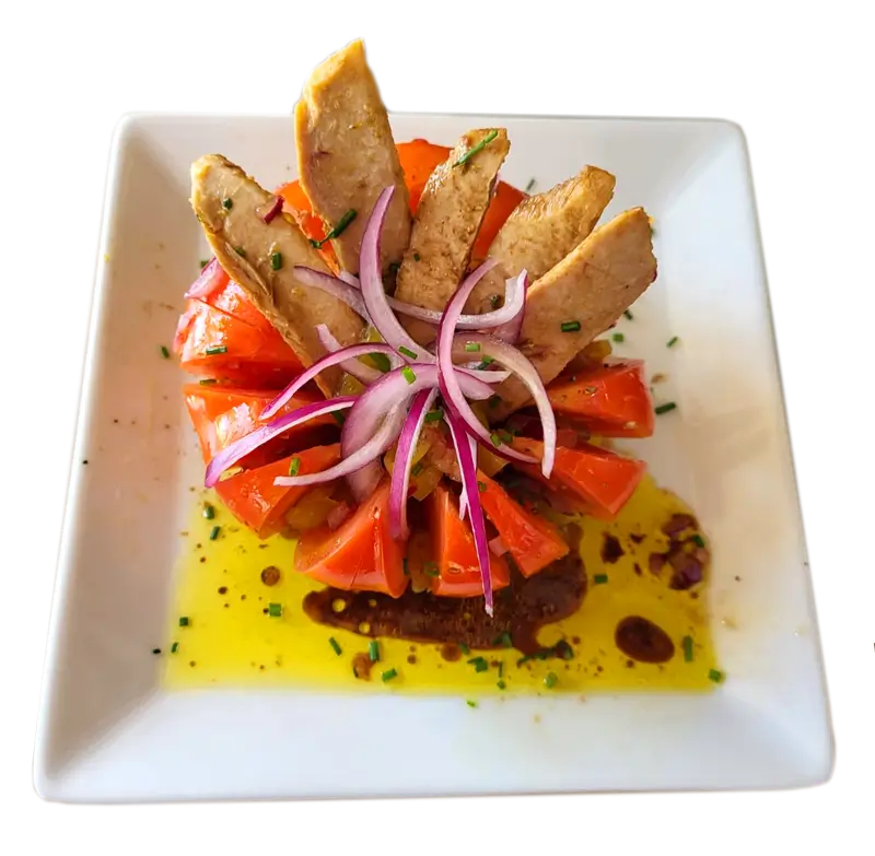 Plato de tomate aliñado con ventresca, cebolla roja y piparras.